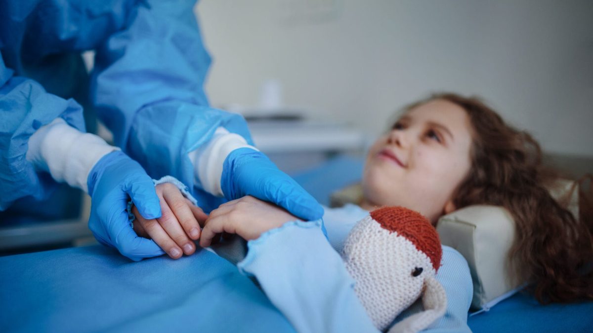 close up of doctor taking care of little girl in hospital ward after dermoid cyst surgery.