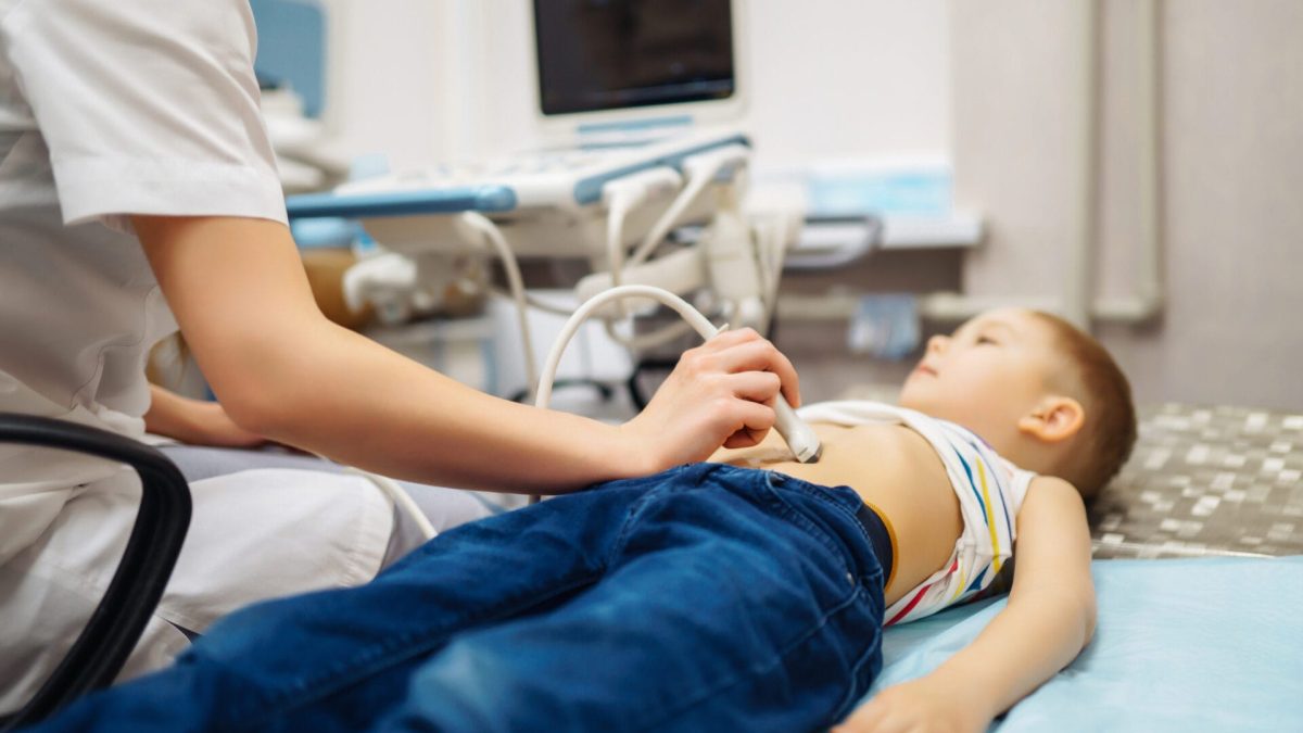 boy undergoing ultrasound examination. doctor examining kid stomch in clinic with equipment before Appendectomy.