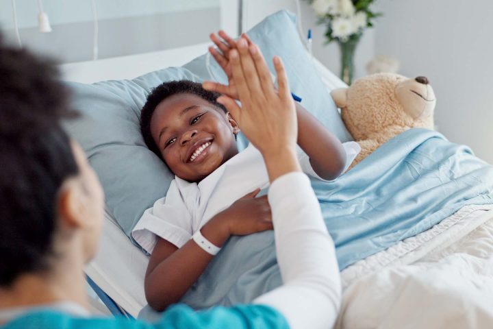 High five, nurse and black child patient in hospital for success of surgery for congenital heart disease. Checkup, sick and cardiology medical worker with African kid in bed for postoperative care.
