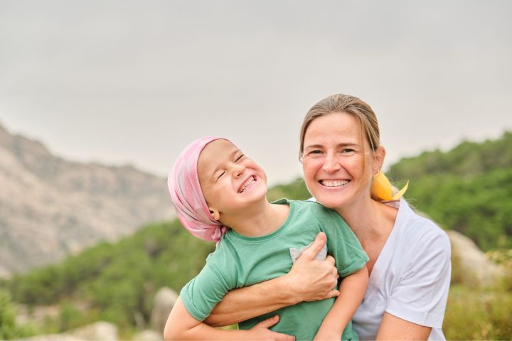 childhood tumors | Child with pediatric tumors, and mother smiling outdoors together